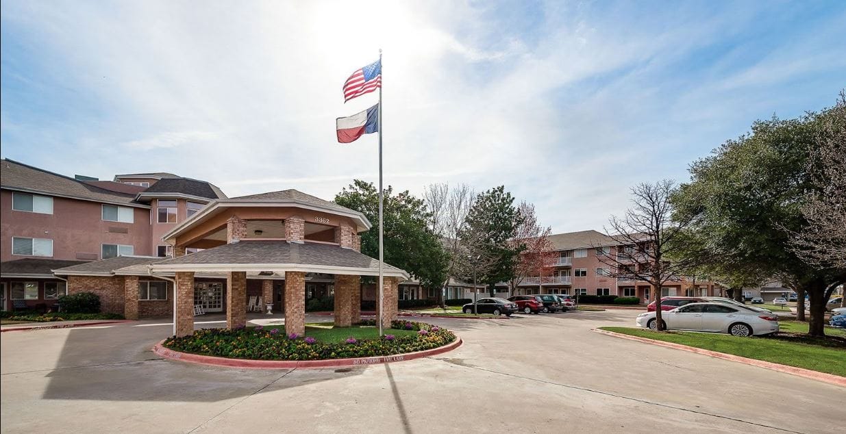 Main entrance of a senior living facility with flags