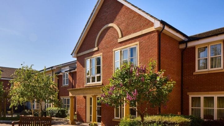 Hallmark Admiral Court, memory care — Brick building with landscaped gardens and blue sky