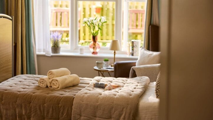 Hallmark Admiral Court, memory care — Cozy bedroom with neatly arranged towels and flowers