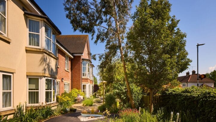 Hallmark Admiral Court, memory care — Sunny garden pathway beside residential buildings