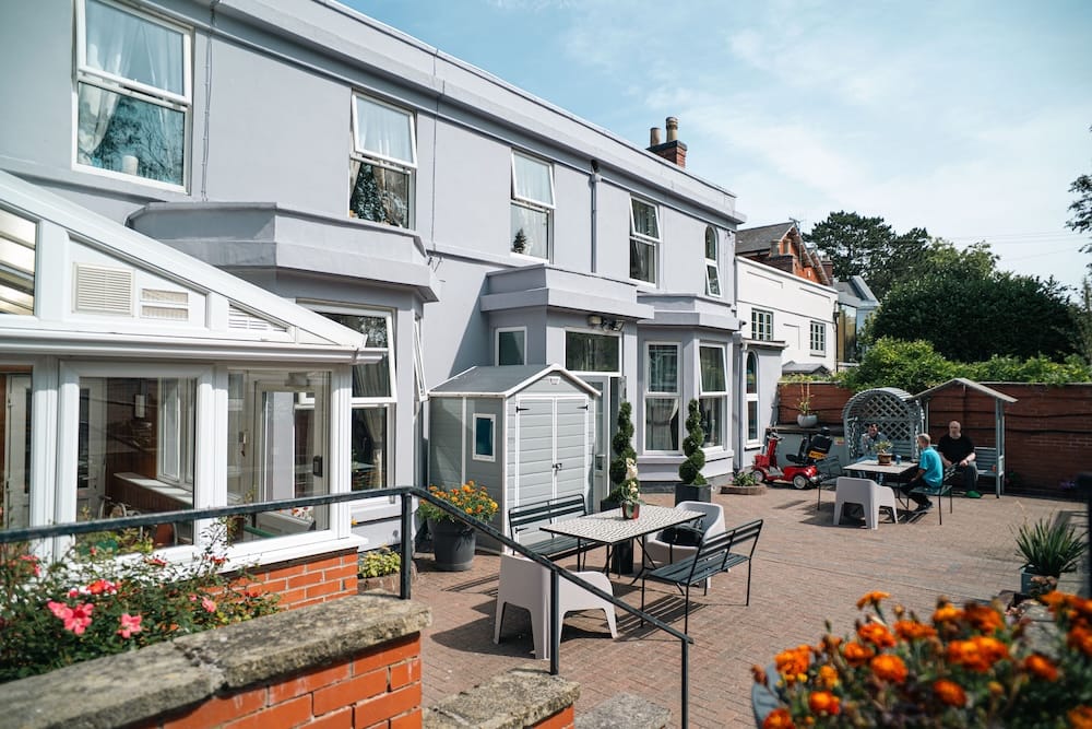 Exterior view of a care home with outdoor seating area