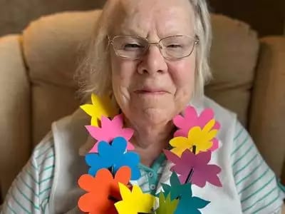 Resident celebrating with colorful flowers necklace.