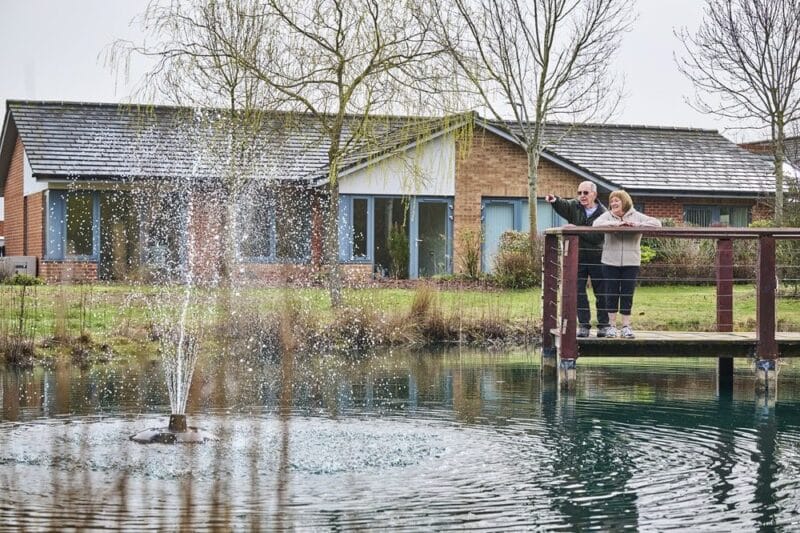 Residents enjoying a peaceful outdoor area by the pond.