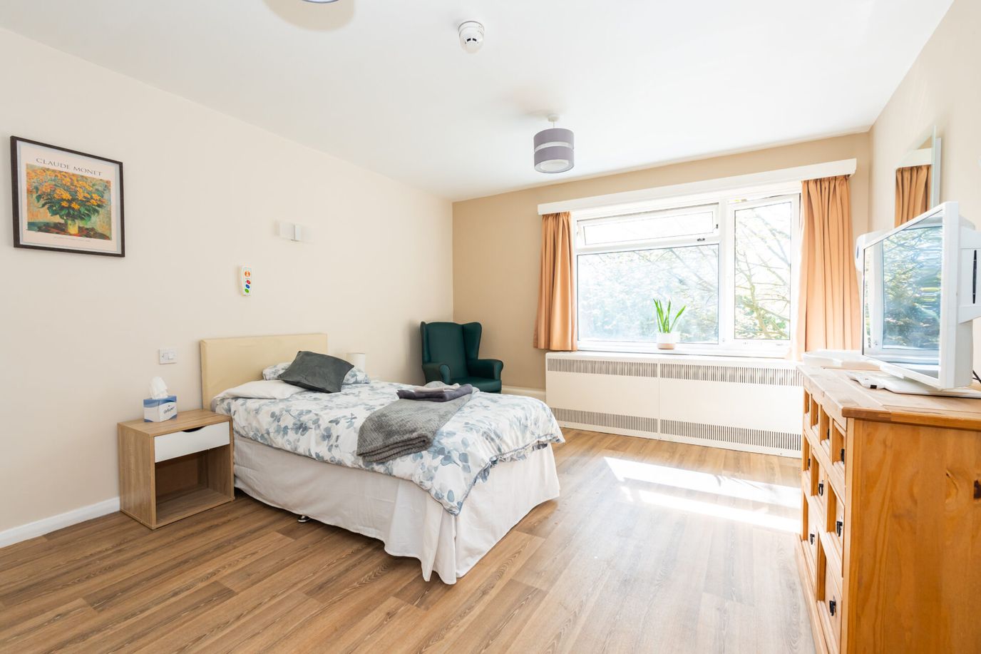 Brightly lit resident room with a bed and chair