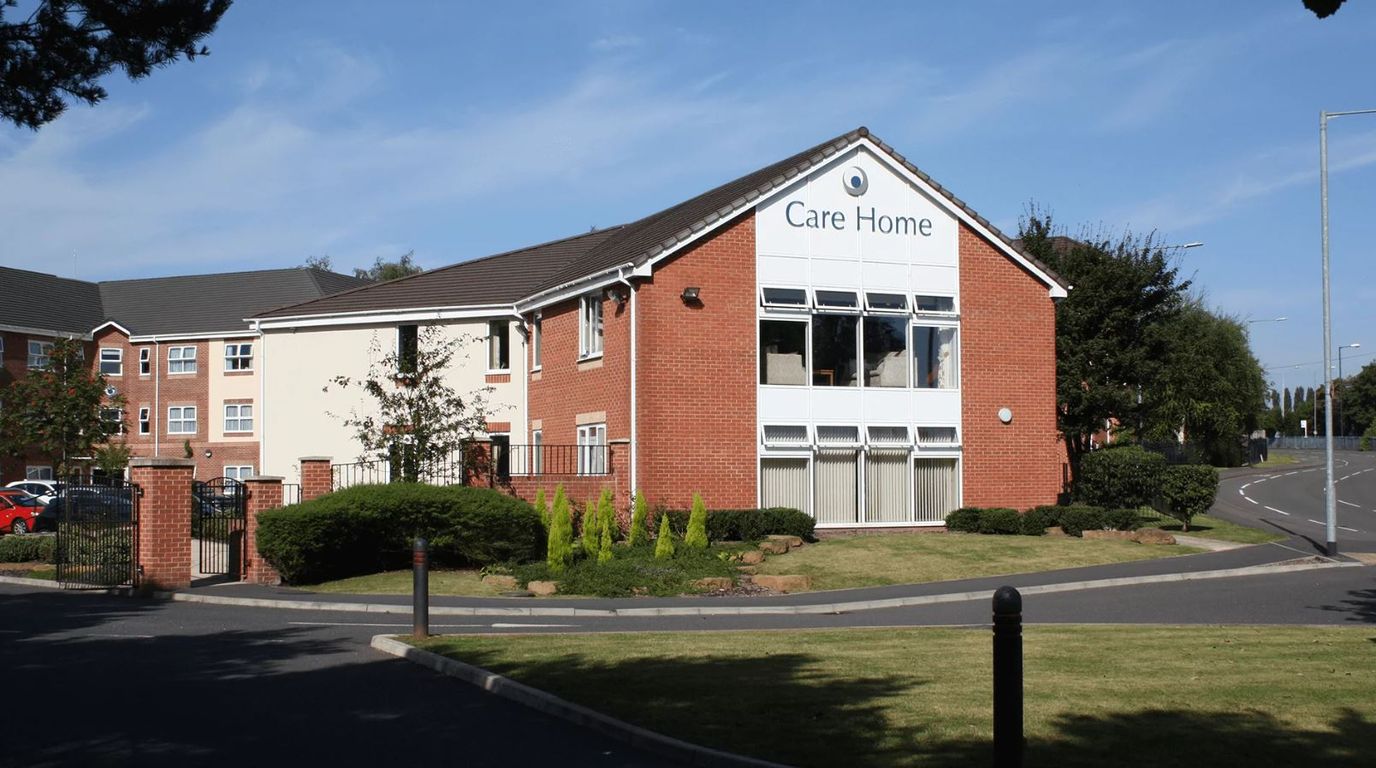 Exterior view of a care home building with landscaped greenery