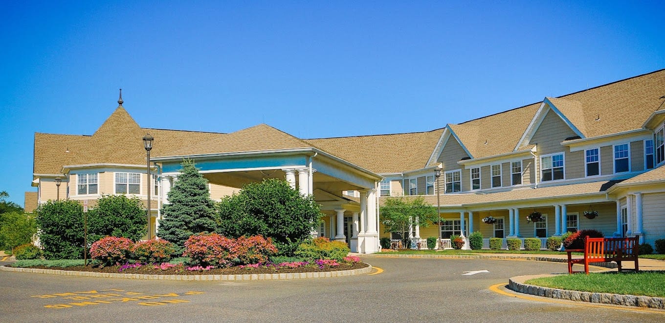 Exterior view of a senior living facility with gardens and seating