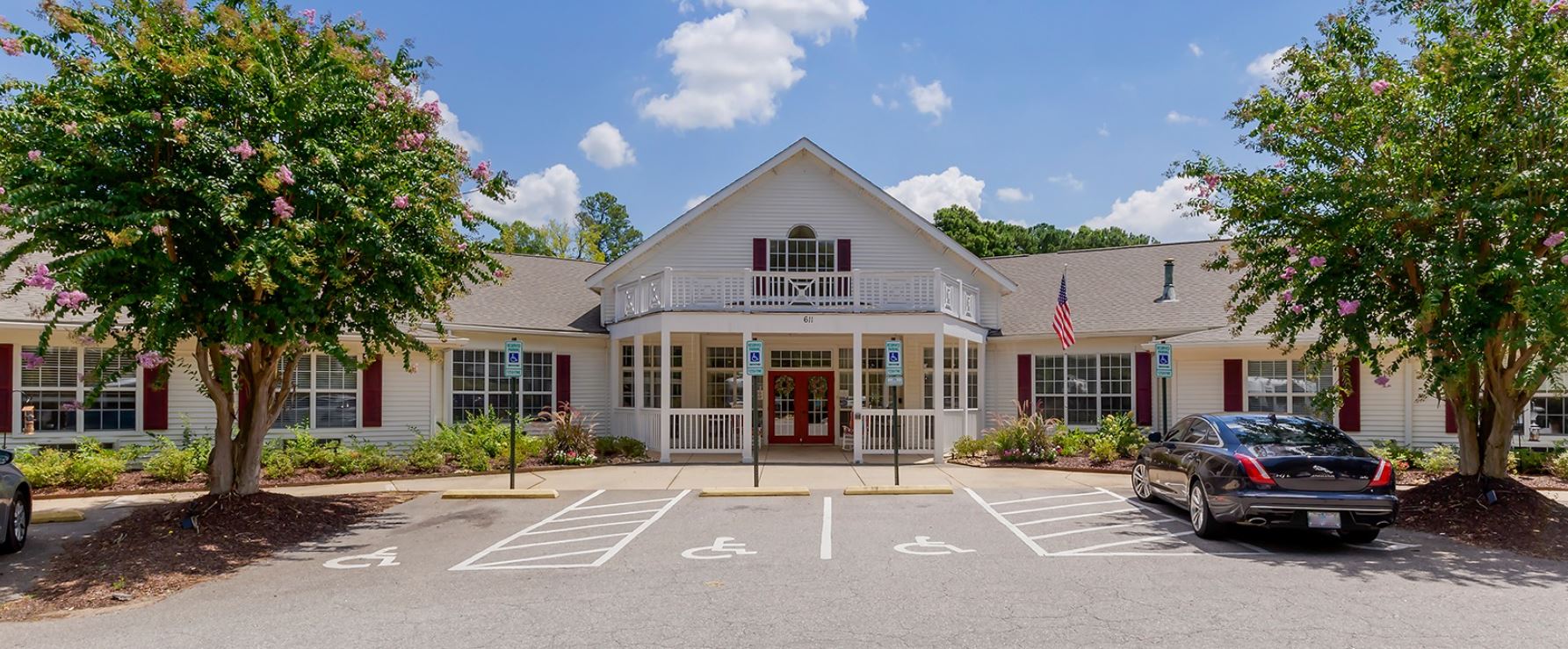 Exterior view of a senior living facility with parking and gardens