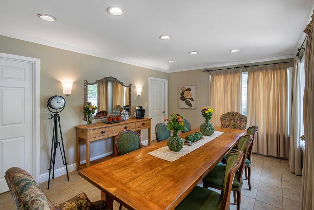 Bright dining room with a large wooden table and flowers