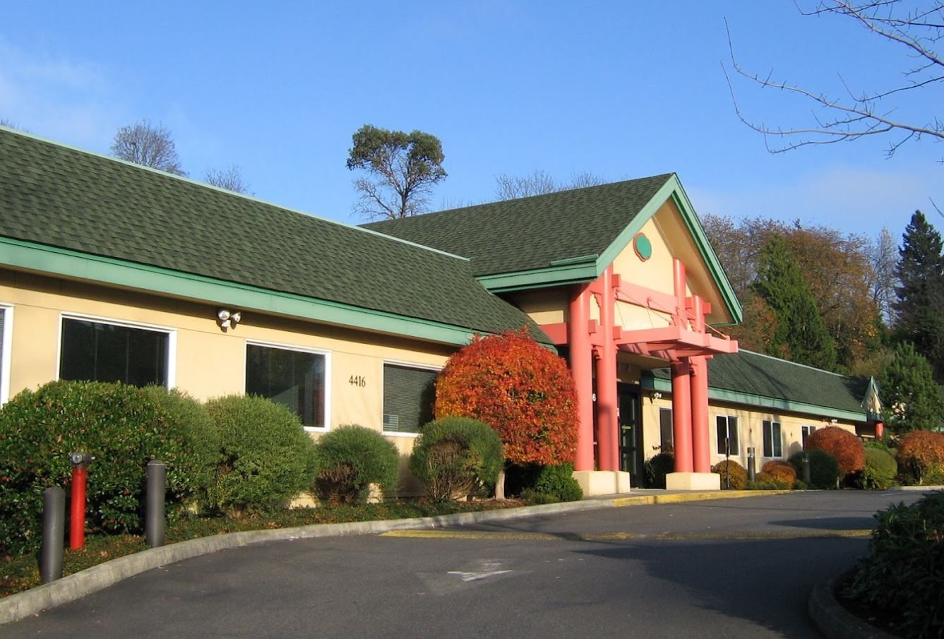 Exterior view of a senior living facility surrounded by gardens