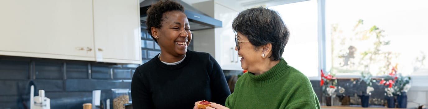 Care staff and resident smiling together in a kitchen