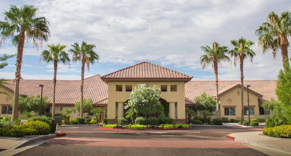 Exterior view of a senior living facility with palm trees
