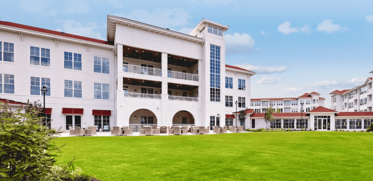 Exterior view of a senior living facility with green lawn
