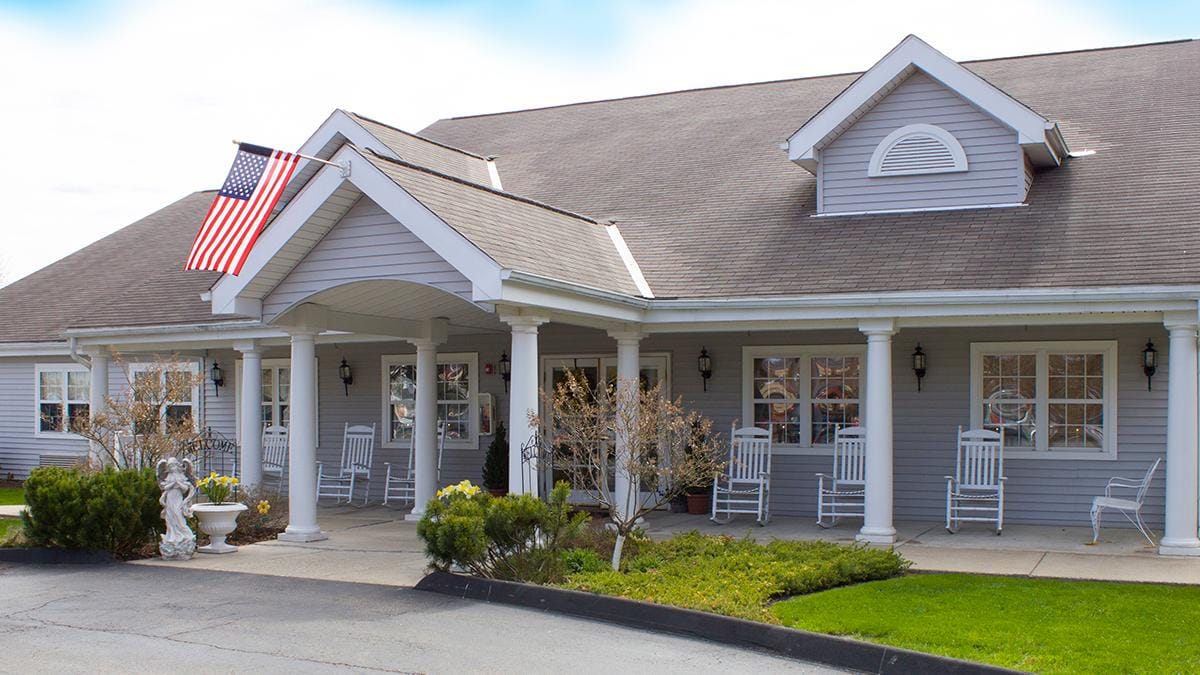 Front entrance of The Addison of Uniontown with rocking chairs and landscaping