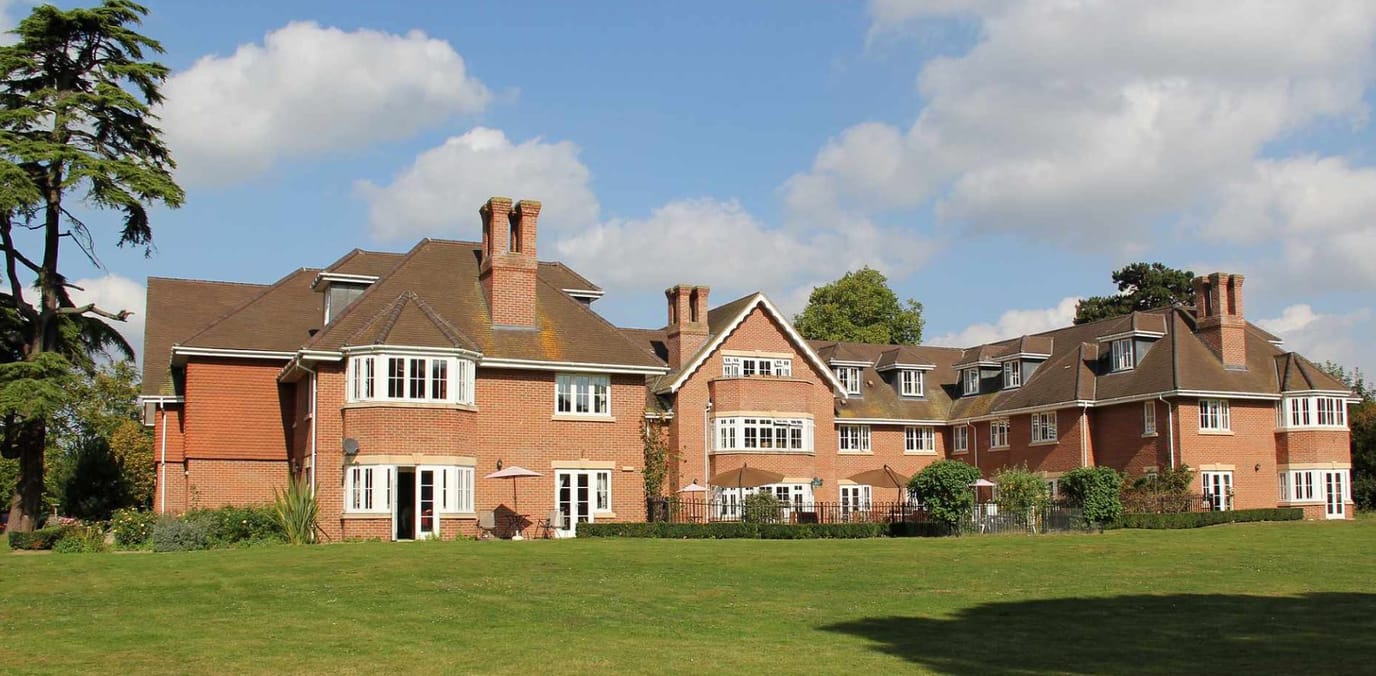 Exterior view of The Manor Care Home surrounded by green space