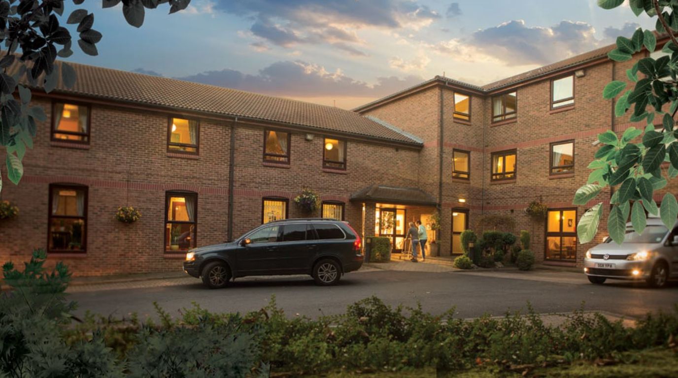 Exterior view of Ferguson Lodge with cars and residents