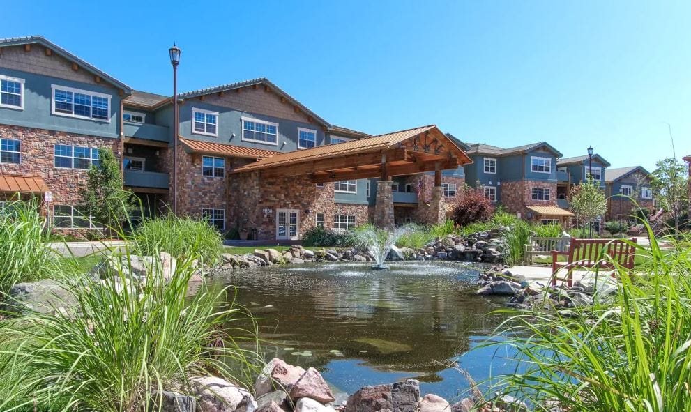 Exterior view of Keystone Place at Legacy Ridge with pond and landscaping