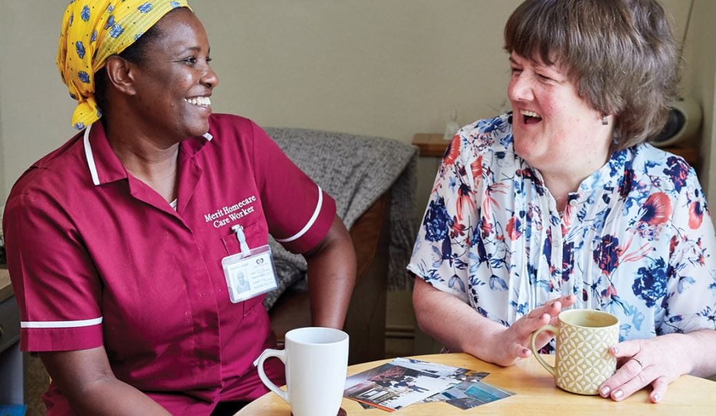Caregiver and resident sharing a joyful moment indoors.