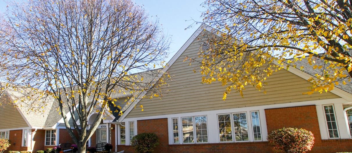 Exterior view of a cozy senior living facility with autumn trees