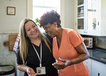 Caregiver and senior client laughing in the kitchen