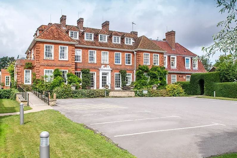 Exterior view of Rush Court Care Home surrounded by green spaces