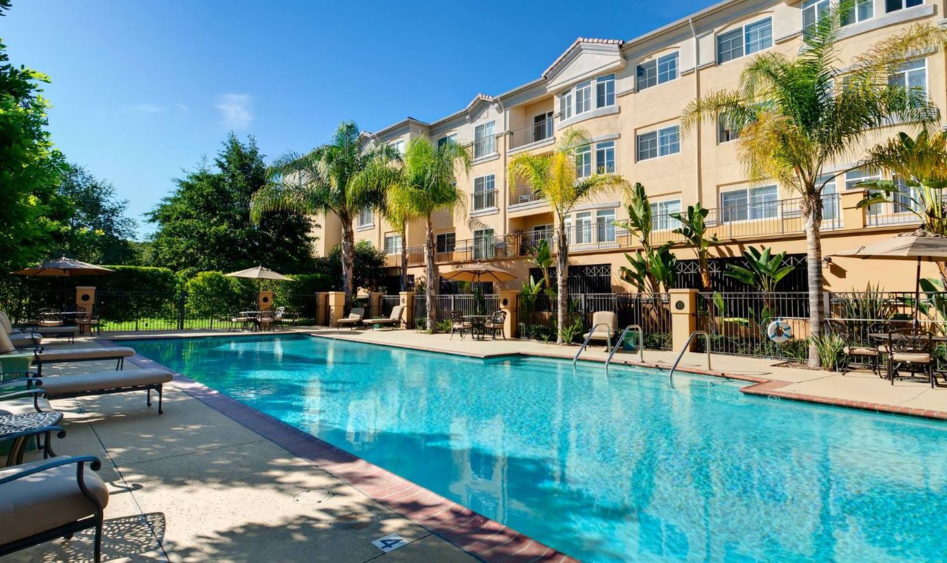 Outdoor pool area with seating and palm trees