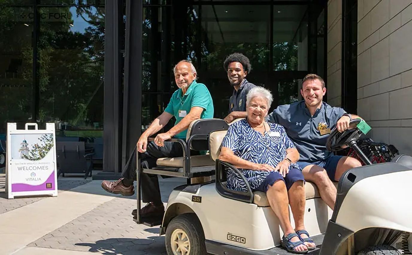 Residents and staff outside enjoying a golf cart ride