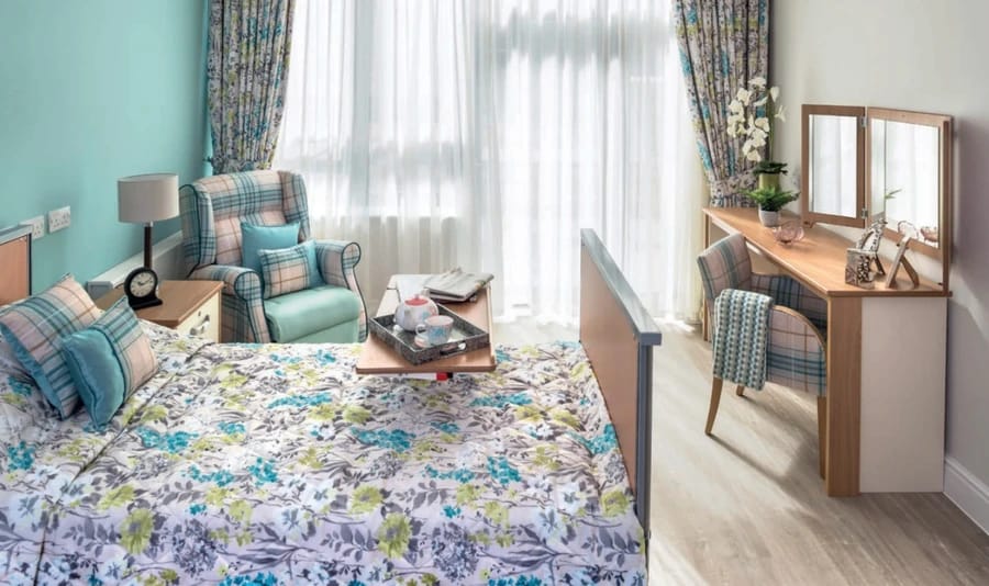 Cozy resident room with floral bedding and natural light.