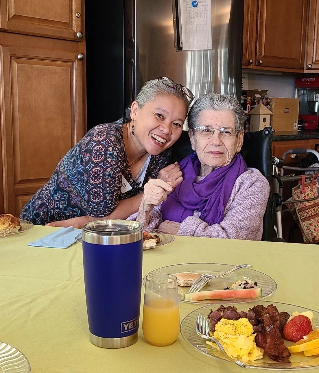 Resident and staff sharing a joyful moment over a meal.
