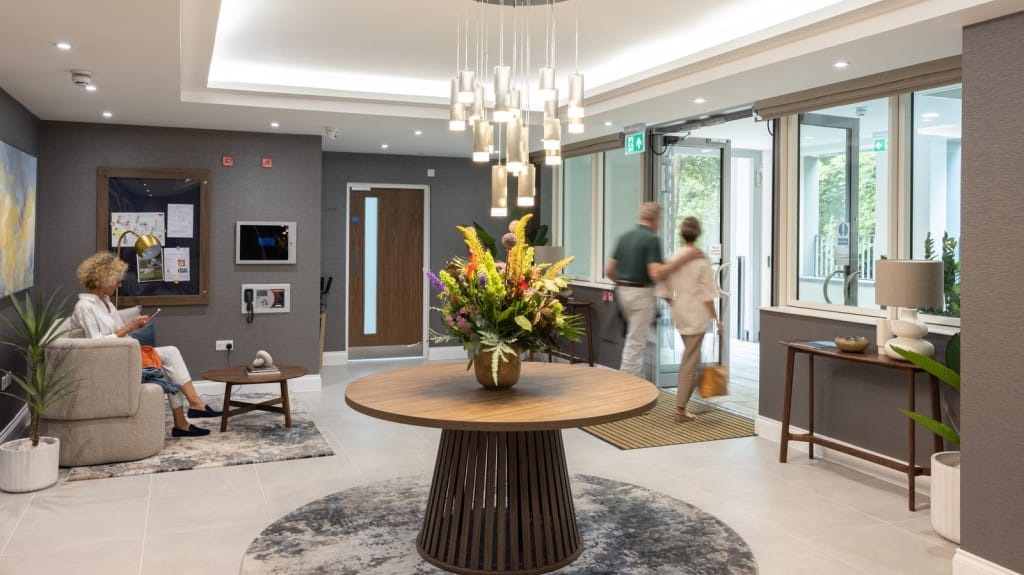Bright, inviting lobby area with residents and flowers.