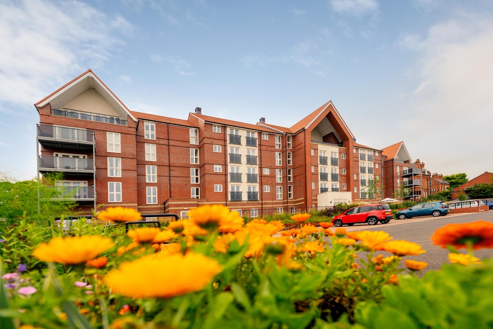 Exterior view of the Savoy House building surrounded by flowers.