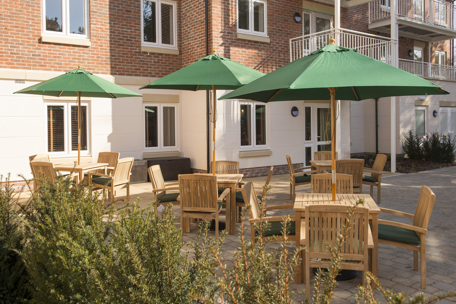 Outdoor seating area with green umbrellas and wooden tables