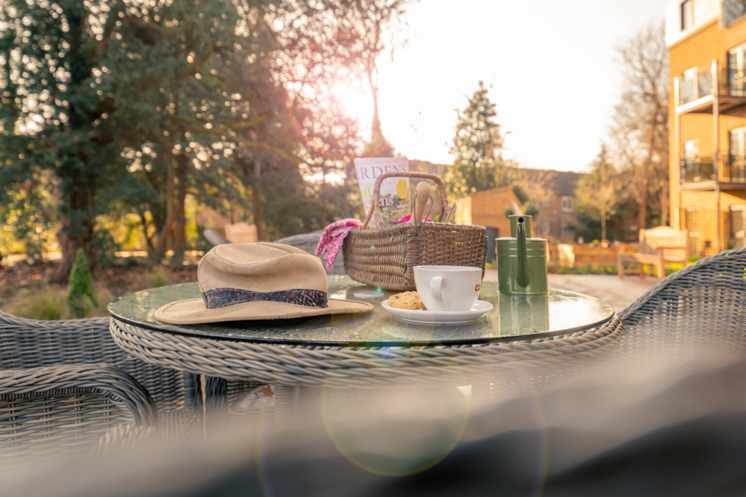 Table set with a hat, drink, and a magazine outdoors.