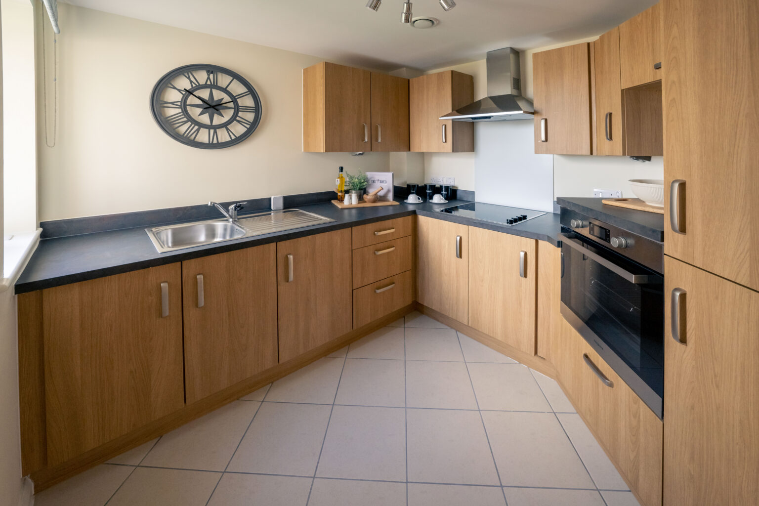 Modern kitchen with wooden cabinets and clock.