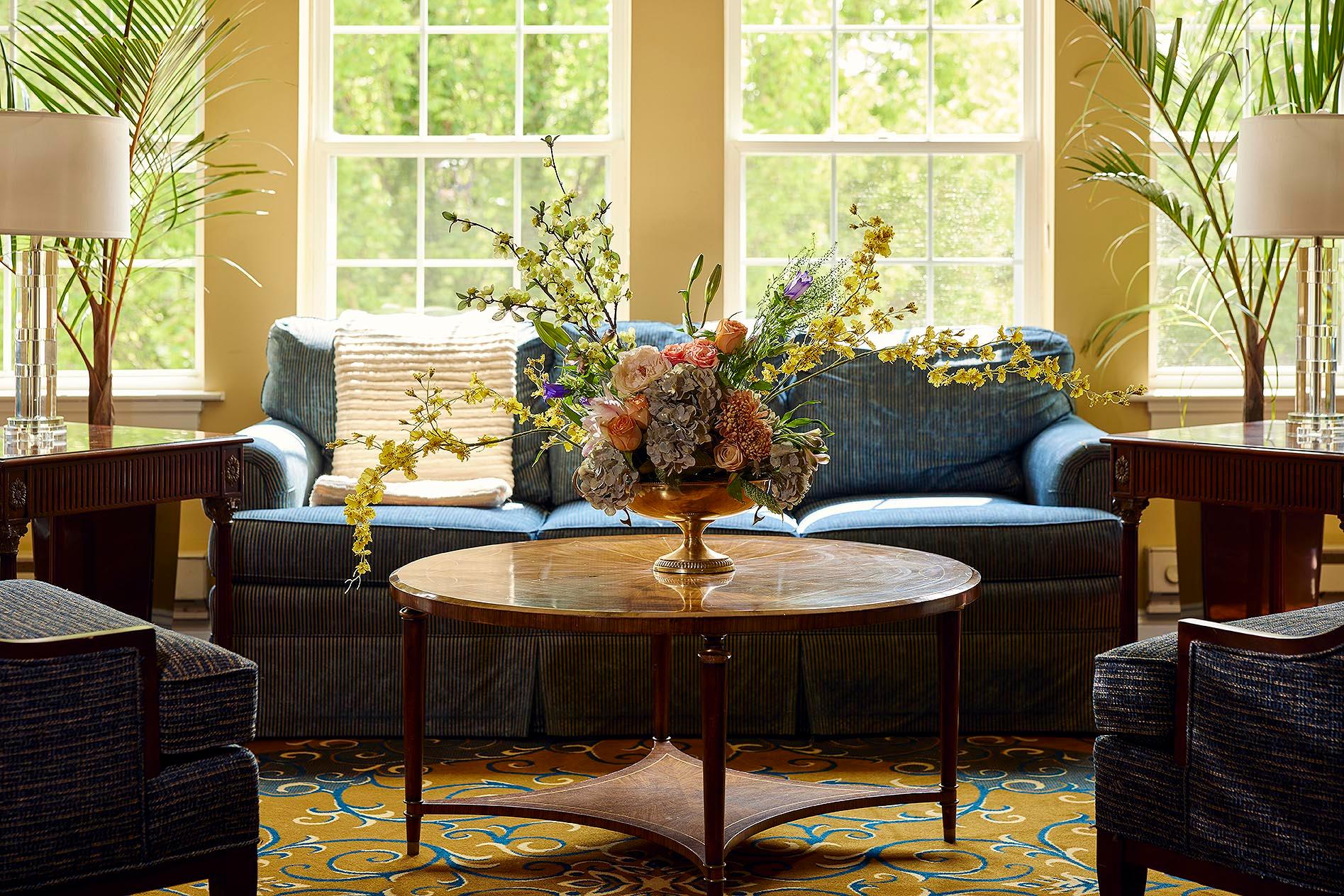 Bright common area with comfortable seating and floral arrangement