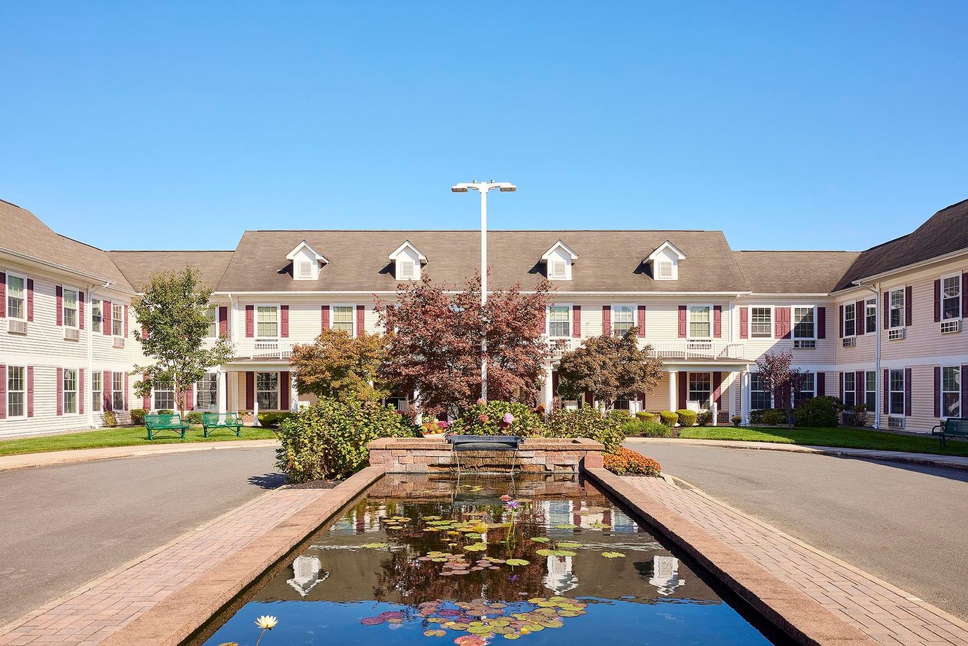 Exterior view of a senior living facility courtyard with a pond