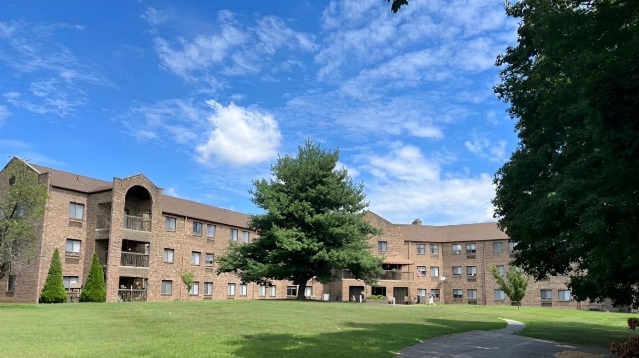 Exterior view of a senior living facility with grassy area