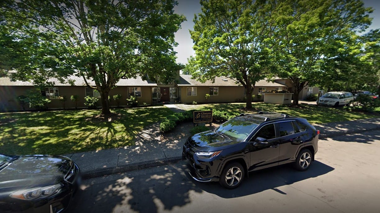 Exterior view of Chateau Gardens Memory Care with trees and cars