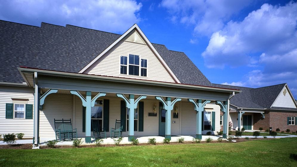 Exterior view of a senior living facility with rocking chairs
