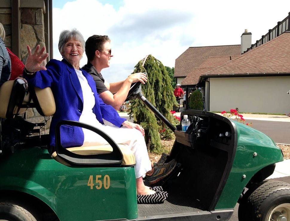 Resident and staff member enjoying a golf cart ride outside