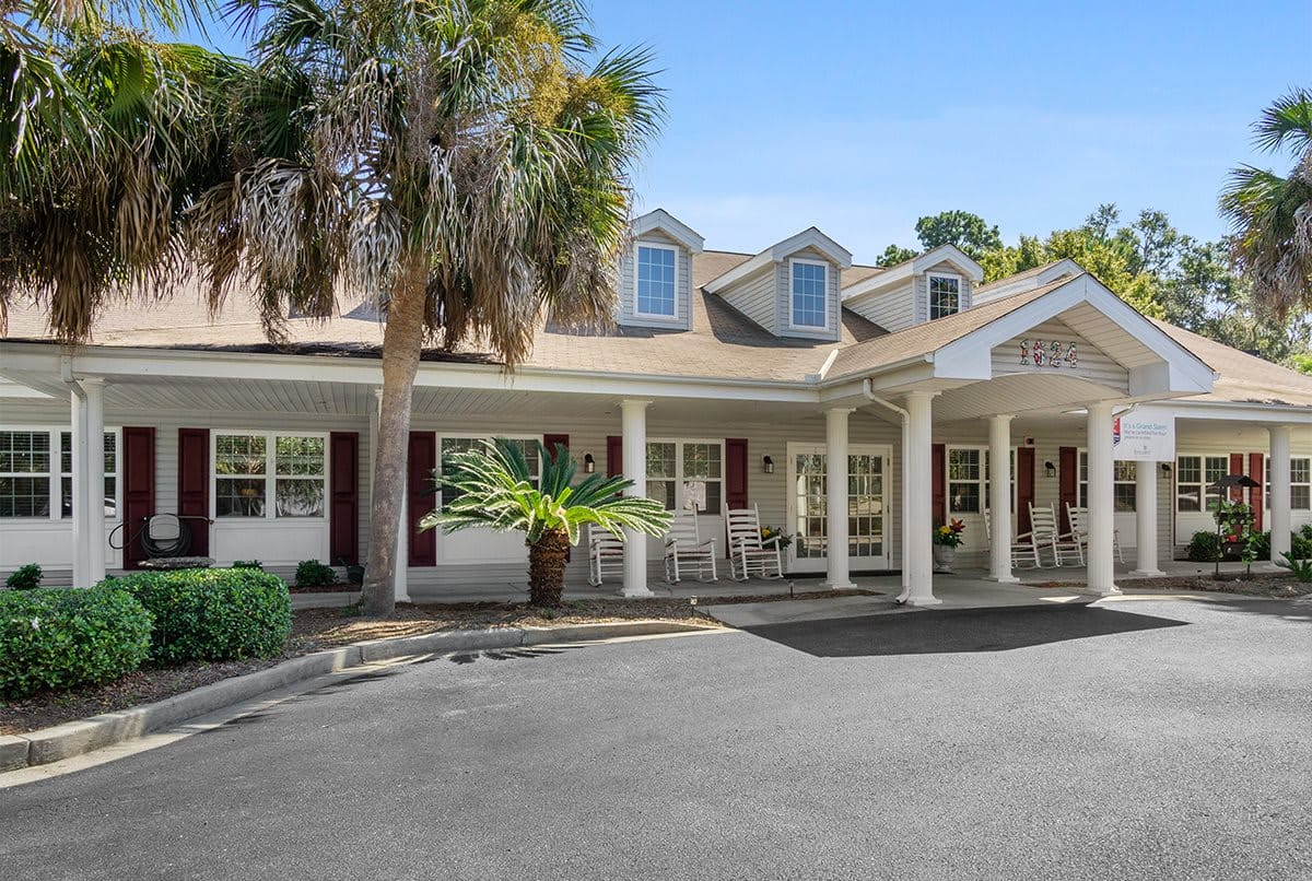 Exterior view of the facility with palm trees and rocking chairs