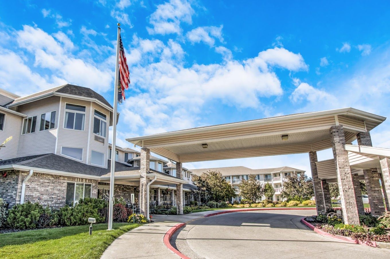 Front entrance of a senior living facility with flag and landscaping