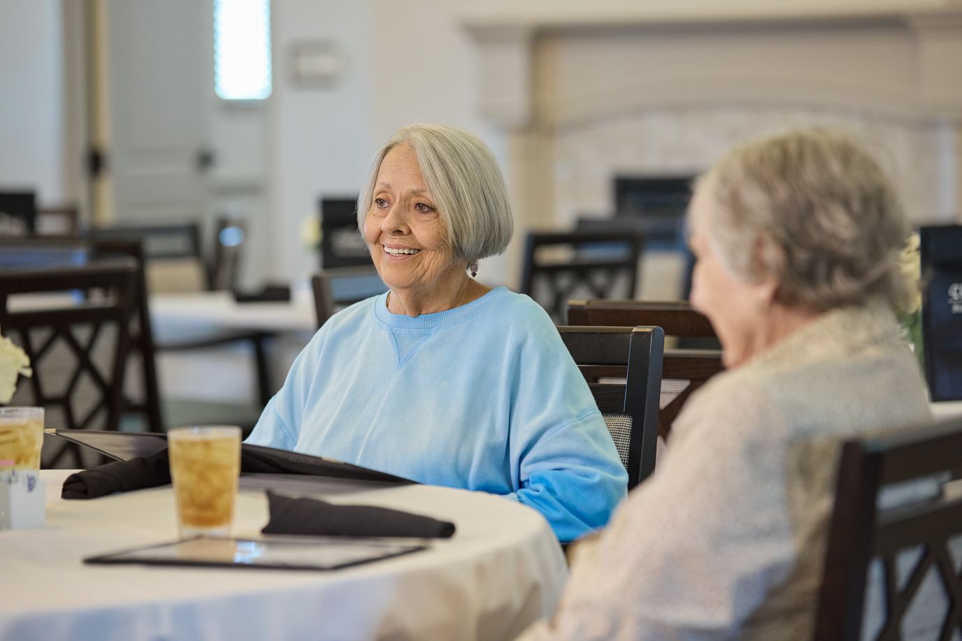 Two smiling senior residents in a dining area
