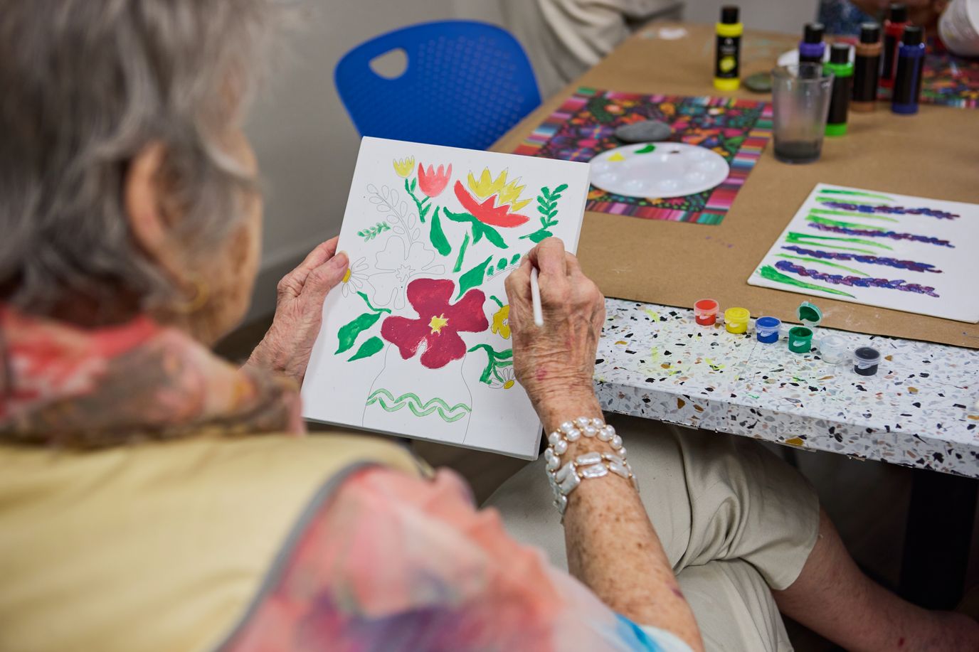 A resident painting flowers in an activity room