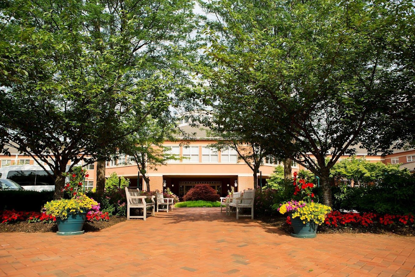 A pathway with benches and flowers in front of the facility