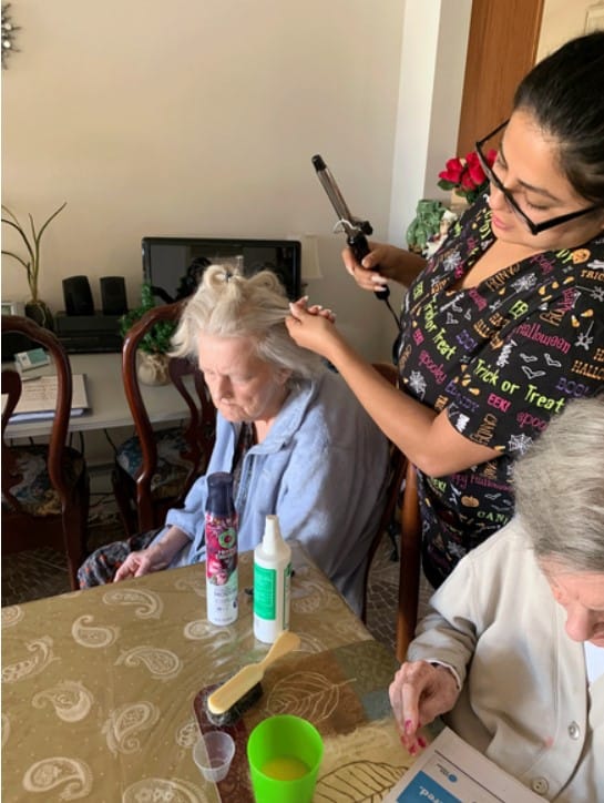 Staff member styling resident's hair in a cozy interior