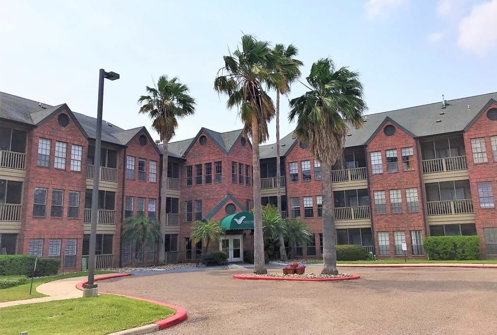 Exterior view of a senior living facility with palm trees