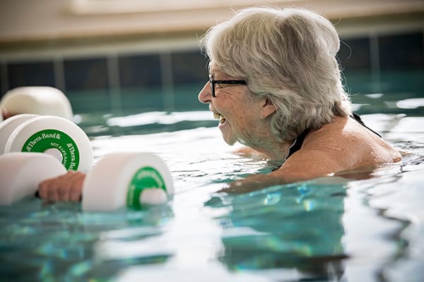 Resident enjoying water therapy with dumbbells in the pool