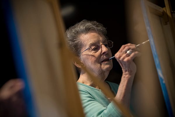 A senior woman painting in an activity room