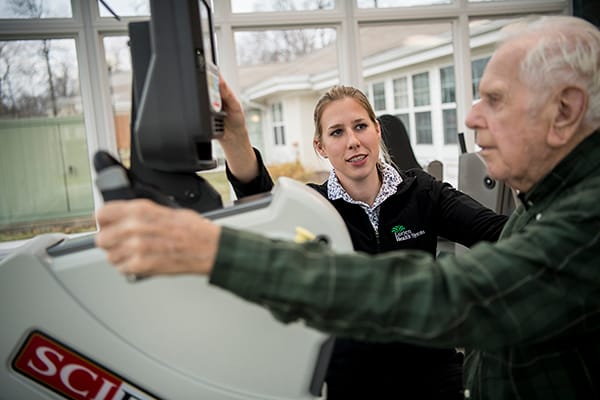 Staff assisting resident with exercise equipment