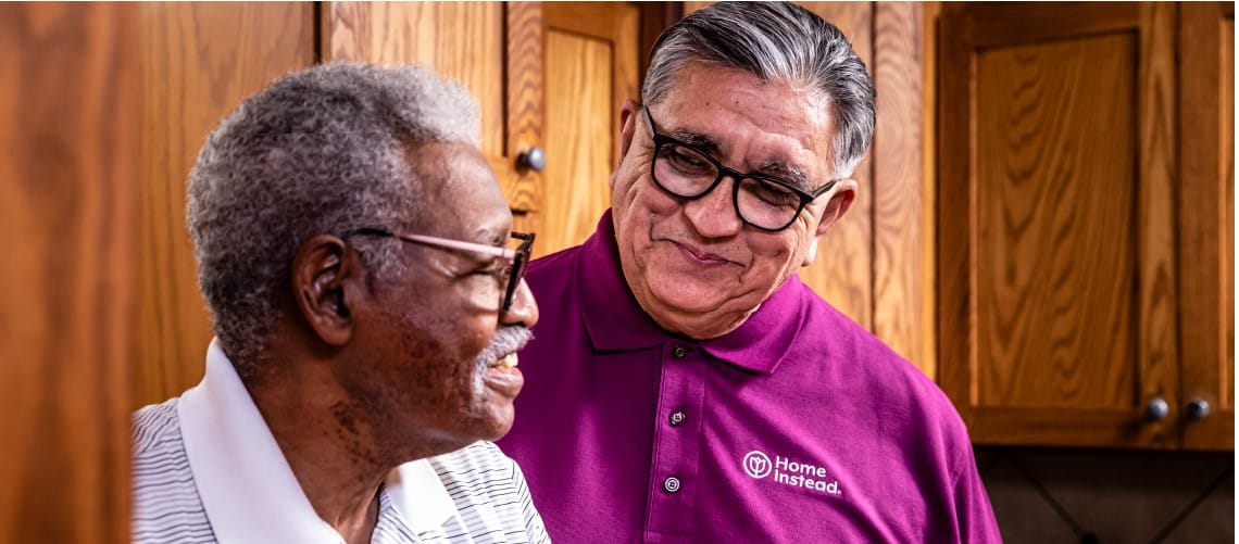 Staff interacting with a resident in a warm kitchen setting